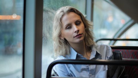 young blonde girl looking out the window on the bus