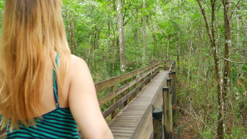 Blonde Female In Dress Walking On Path Through Florida Slough Marsh 01