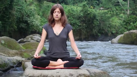 Young woman meditating by the river