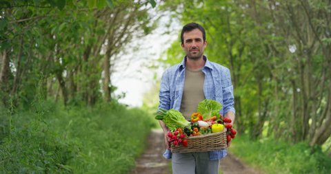 Portrait of a happy young farmer holding fresh vegetables in a basket. On a background of nature The concept of biological, bio products, bio ecology, grown by own hands, vegetarians, salads healthy	