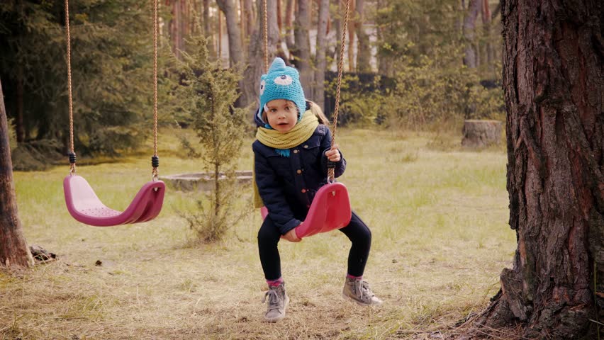 Little girl playing with swings in the forest