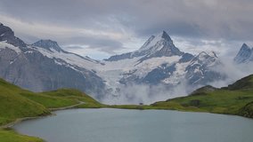 Dramatic summer view of Bachalpsee lake with Schreckhorn and Wetterhorn peaks on background. Foggy outdoor scene in the Swiss Bernese Alps, Switzerland, Europe. Full HD video (High Definition).