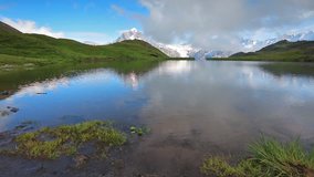 Time lapse clip. Sunny summer morning on Bachalpsee lake with Schreckhorn peak on background. Green morning scene in the Swiss Bernese Alps, Switzerland, Europe. Full HD video (High Definition).