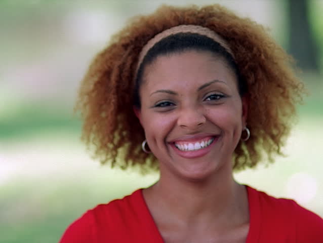 Full-face portrait of a smiling young woman with an aureole of curls