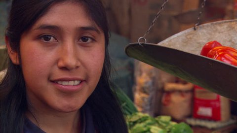 Close-up face of smiling Peruvian girl at a produce market