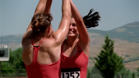 Happy female relay racers congratulating each other before turning to shake hands with rivals