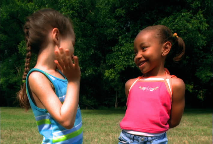 Two little girls hugging as they smile at camera
