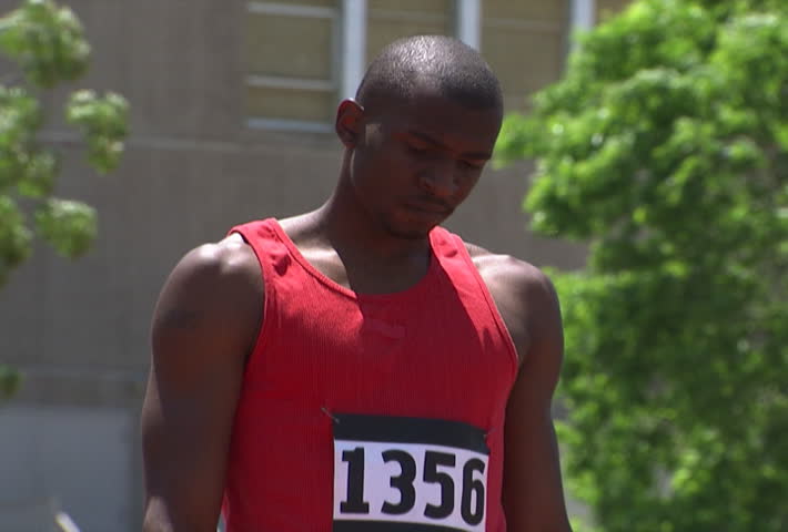A runner doing loosening-up exercises before joining others at the starting line