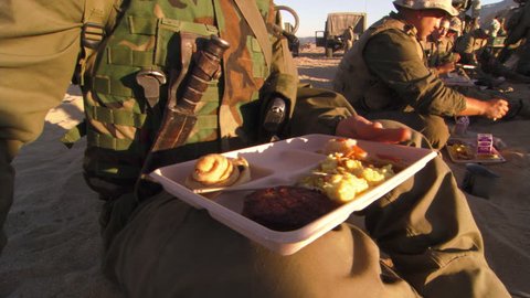Marines in battle dress eating breakfast in desert surroundings