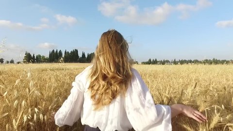 Happy young woman running in wheat field.
Slow motion