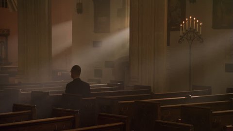 Man kneeling and praying in nave of Catholic church