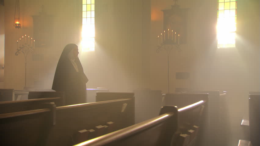 Nun walking slowly up aisle of Catholic church, votive candles in foreground | Shutterstock HD Video #26509235