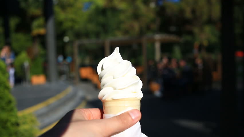 A man is eating fast food ice cream against the background of a blurry city street.
