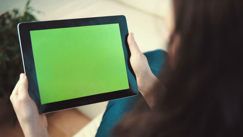 Indoor shot of a woman using tablet pc with green screen sitting on white sofa, pick and slide gestures, horizontal orientation Royalty-Free Stock Footage #26519735