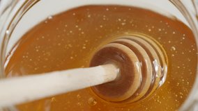 Sweet food substance and wooden dipper - Spiral kitchen utensil in glass honey jar close-up 3840X2160 UHD video