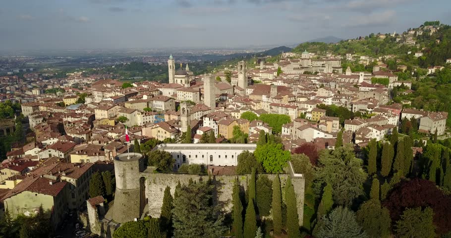 Drone aerial view of Bergamo - Old city (Città Alta), Italy. Landscape on the city center, the main square, the old fortress and its historical buildings during a wonderful blu day