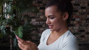 Attractive smiling African-american woman make up using smartphone.