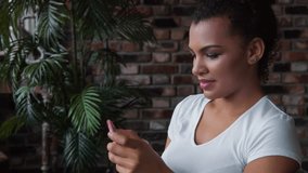 Attractive smiling African-american woman with make up using smartphone.