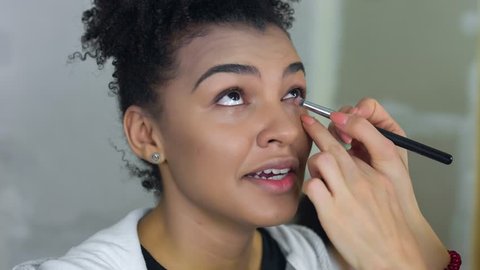 Professional make-up artist makes makeup of afro-american model. Beauty and fashion concept.