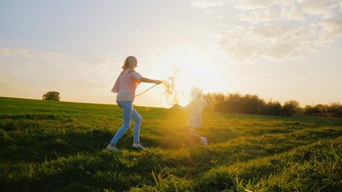 Activity at any age. A middle-aged woman is playing with her daughter, running around the field, having fun. Concept - a healthy lifestyle, a happy childhood
