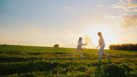 Happy together. Young woman having fun with daughter. Running in a picturesque place, playing with balloons. Concept - children's dreams, active and healthy lifestyle