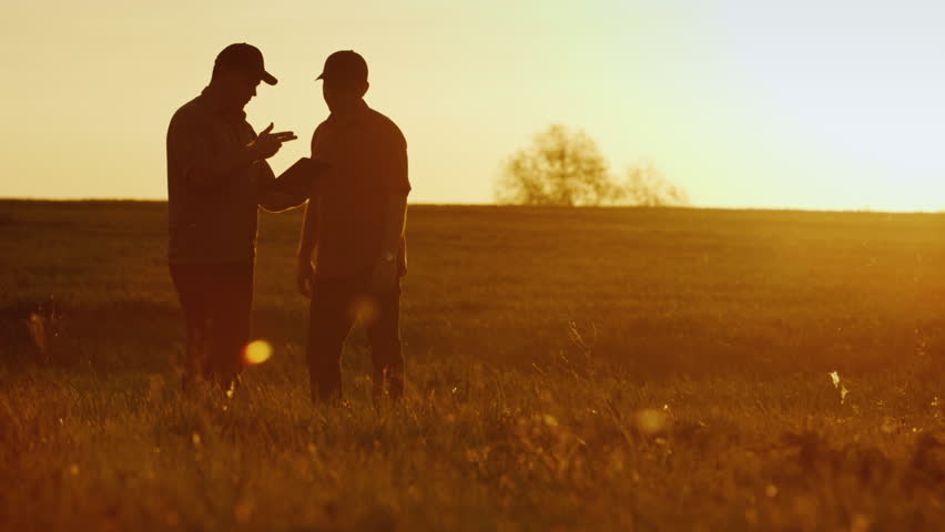 Two businessman farmers shake hands with each other firmly. They talk on the field against a beautiful sunset, they use a tablet. Deal Royalty-Free Stock Footage #26533409