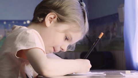 Little girl writing and drawing. Doing homeworks. Child. Adorable girl.