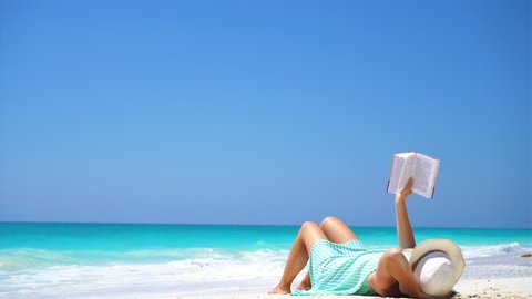 Young woman reading book during tropical white beach