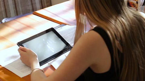 Young girl-freelancer works with a tablet and documents in a cafe. Close-up