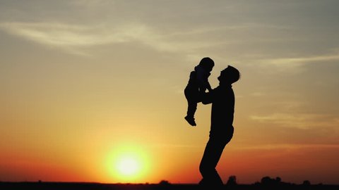 Happy child rushes into hands of father. Family hugs over sunset sky background. Silhouettes of anonymous boy and man outside in summer or autumn landscape. Slow motion 180fps