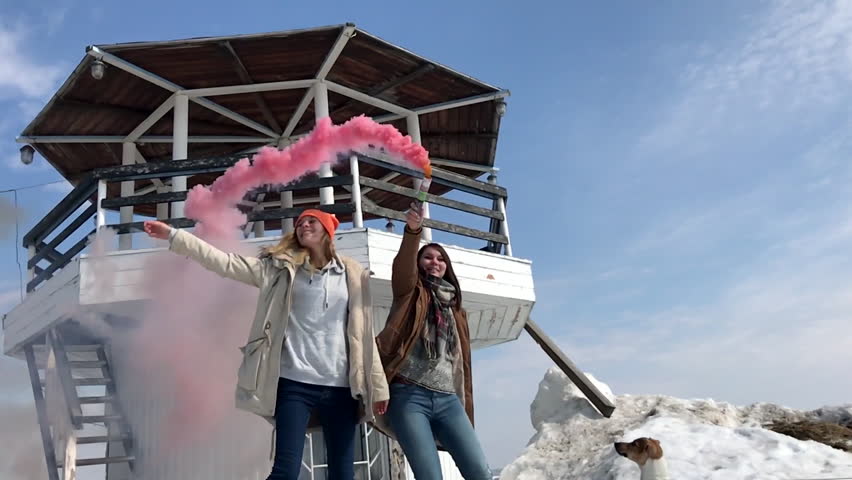 Slow Motion. Two Girls With Colored Smoke at the Lookout Tower on the Beach