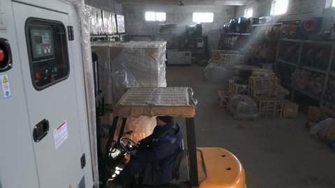 Diesel Forklift Truck lifts a large load nad leaves the warehouse. Working in the warehouse.