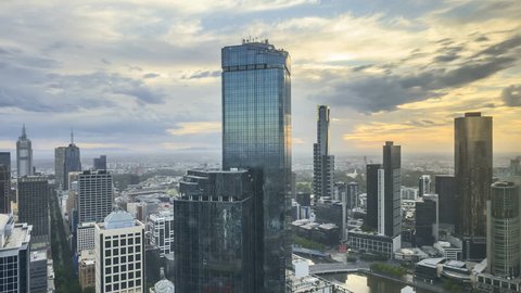 Rolling Clouds, sun rays burst through the clouds during sunrise summer. 4k time lapse of Melbourne city skyline, view from high level building. Zoom out