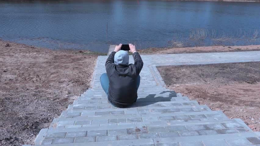 Man sitting on stairs and take pictures on tablet