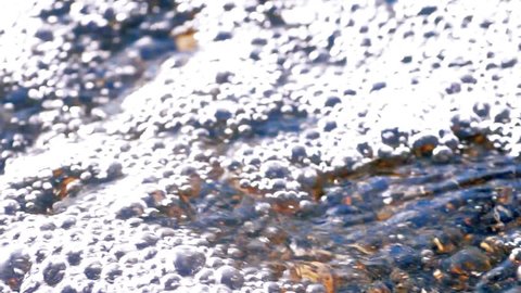 Transparent water flows through small multicolored pebbles