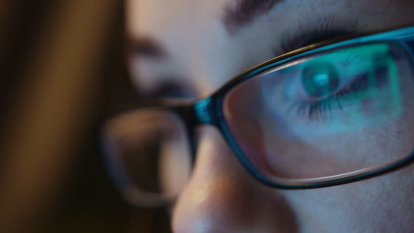 Young business woman in glasses working in the office on the laptop. Close up. The image of computer screen in the glasess.