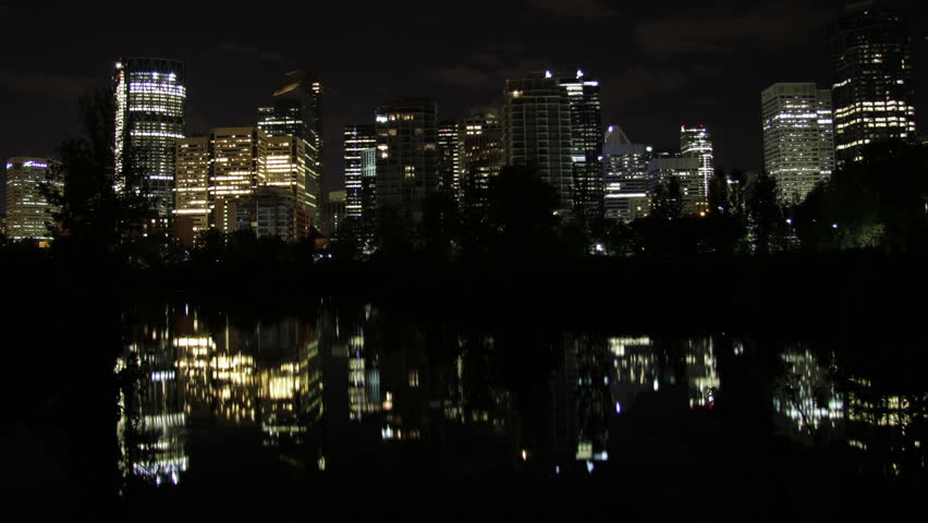 The night skyline of Calgary Alberta Canada reflects in a pond in stunning