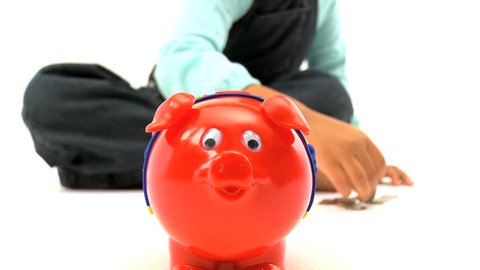 Cute little african american child puts coins into a moneybox 