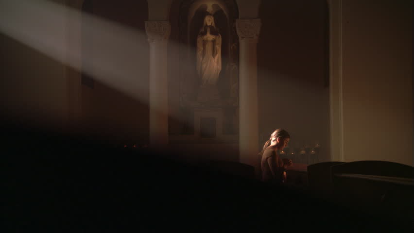 Woman kneeling in ray of sunlight in Catholic church | Shutterstock HD Video #26580902