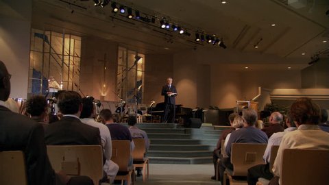 Pastor closing sermon, congregation rising, zoom-in to praying pastor