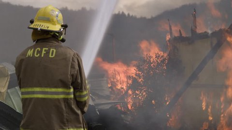 Fireman shoots a powerful stream of water onto a raging structure fire