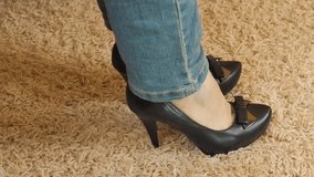 A woman takes off her shoes in heels. Legs of a girl in jeans and shoes. Hands massaged tired feet.