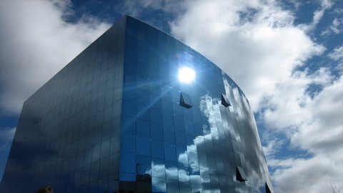 LEON, SPAIN - CIRCA NOVEMBER 2011: Time lapse of people walking past as clouds fly over a glass modern building circa November 2011 in Leon, Spain.