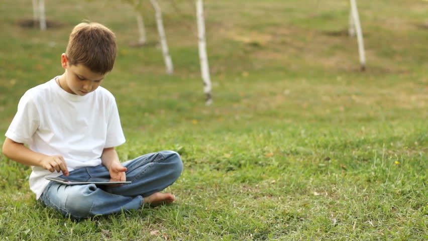 Boy using tablet computer outdoors.
