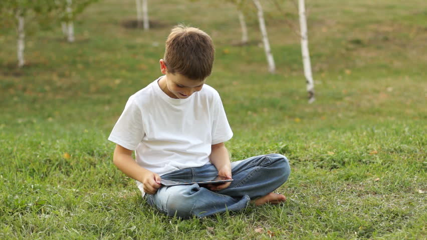 Boy using tablet computer outdoors. Thumbs up.