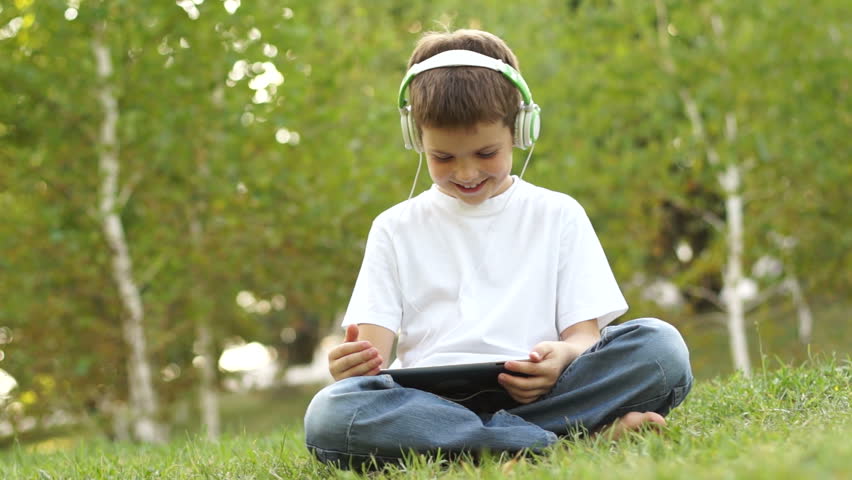 Schoolboy with a tablet pc. Emotional listening to music.