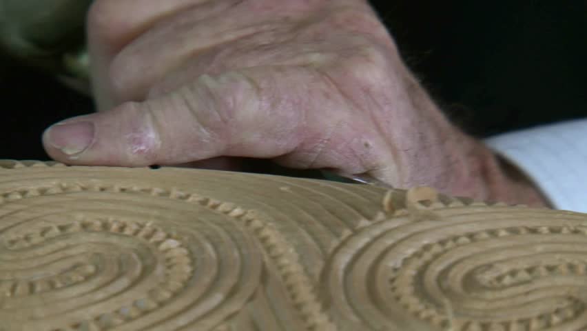 craftsman carver working with kauri wood, creating a maori art sculpture