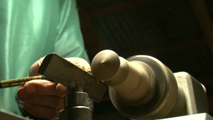 man working on wood lathe creating a wooden âspinning topâ 
