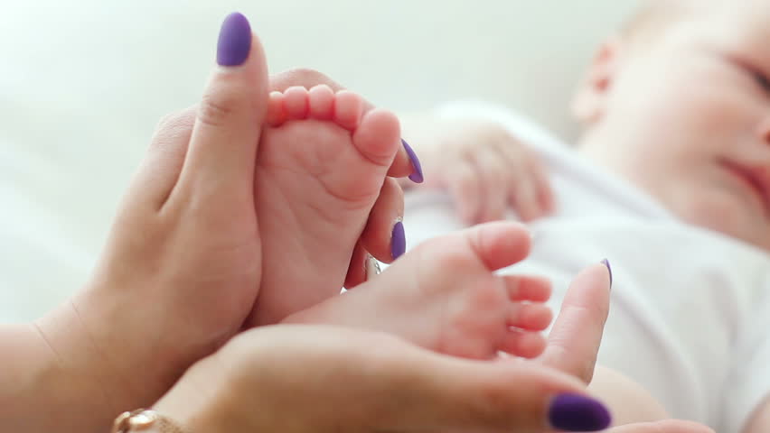 mother holding newborn baby feet and caresses them with his love