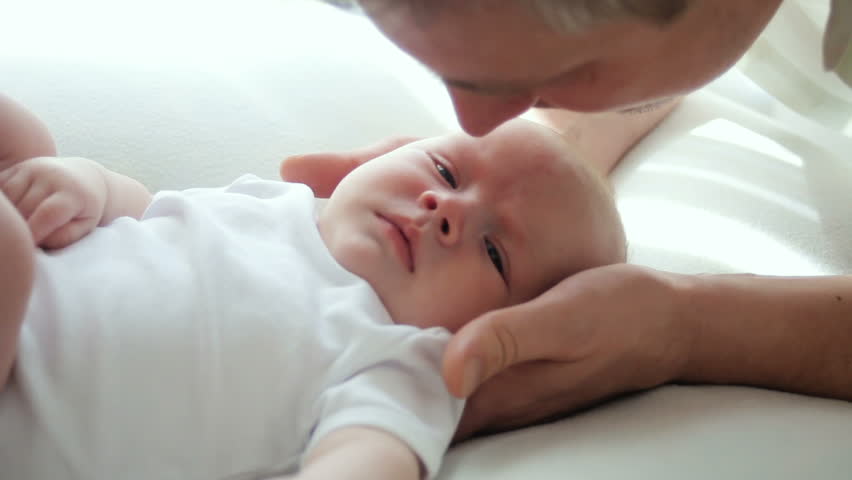 Young father kissing and playing with his baby laying on the bed Videos ...